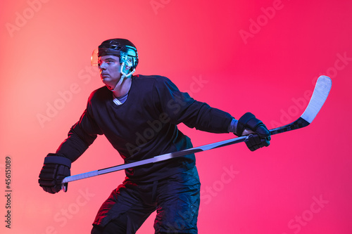 High concentration. Portrait of male hockey player training on gradient background