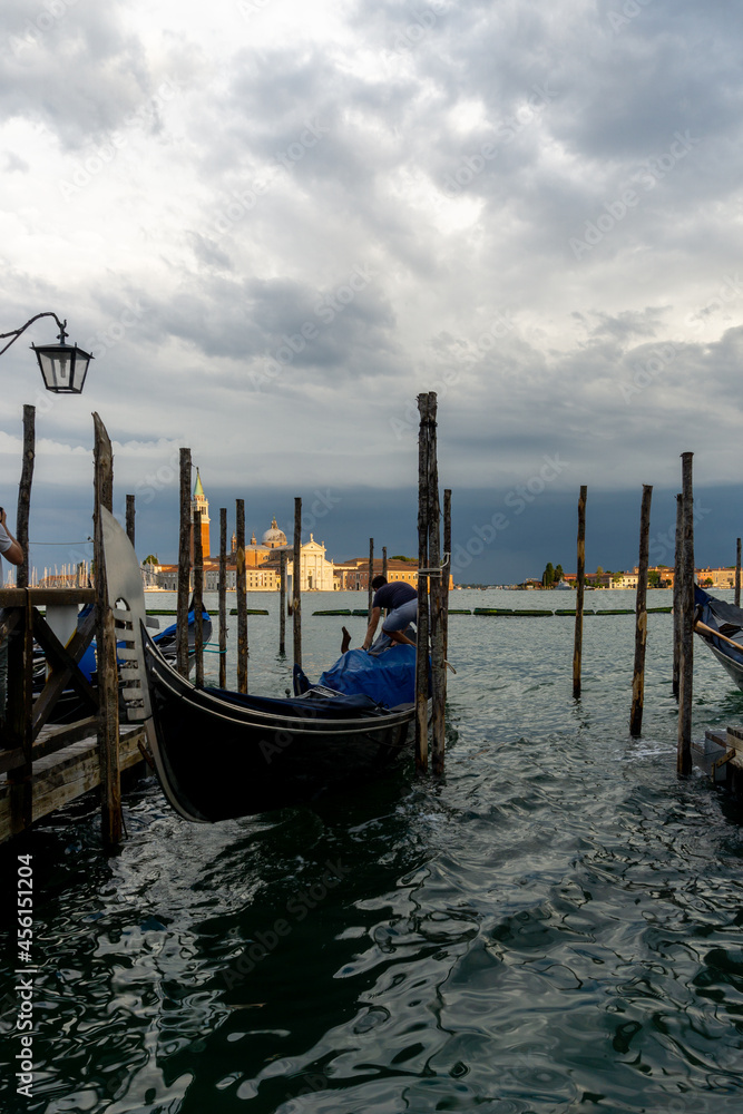 
The gondolas of Venice parked, with the Venetian church in the background, and a great storm that contrasts with the sunny church