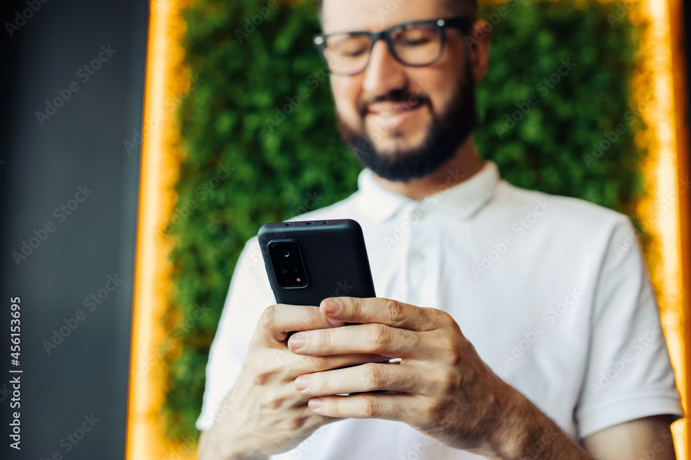 young man with beard sitting in cafe reading text message on mobile phone, Handsome man in cafe using smartphone young man with beard sitting in cafe reading text message on mobile phone, Handsome man in cafe using smartphone