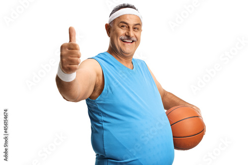Cheerful mature man gesturing thumbs up and holding a basketball © Ljupco Smokovski
