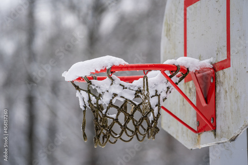 Basketball hoop net after snowstorm filled with snow in winter park  Ukraine. Winter basketball backboard