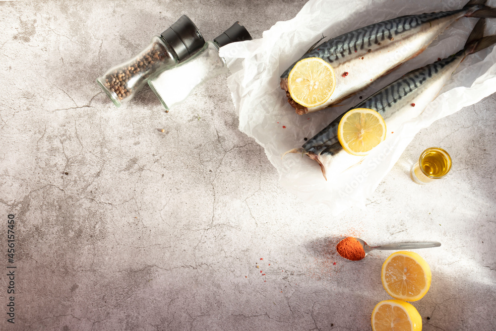 Fresh raw mackerel fish. On a gray background. Raw fish with lemon and dressings Fresh raw mackerel fish. On a gray background. Raw fish with lemon and dressings