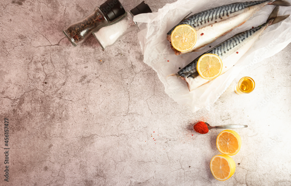 Fresh raw mackerel fish. On a gray background. Raw fish with lemon and dressings Fresh raw mackerel fish. On a gray background. Raw fish with lemon and dressings