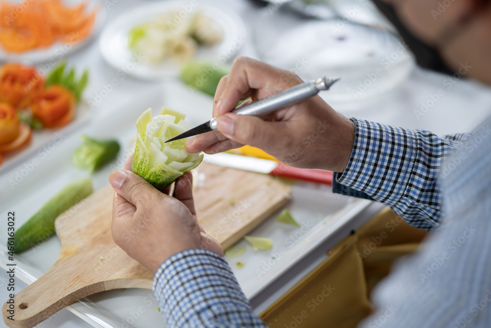 Obraz premium Chef carves patterns on cabbage and other vegetables and fruits for a beautiful table decoration