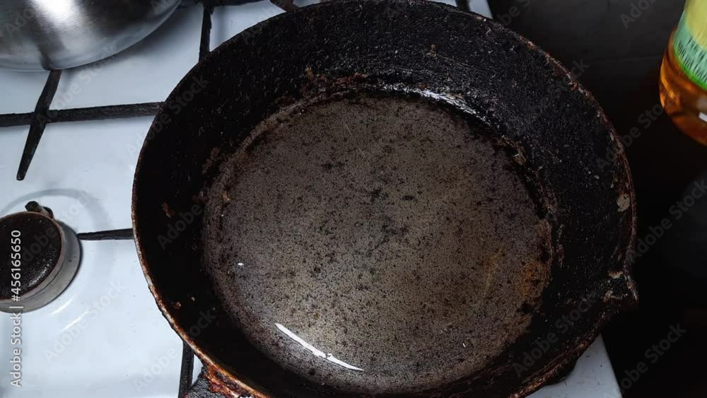 Adding cooking oil to old rustic frying pan for frying Adding cooking oil to old rustic frying pan for frying