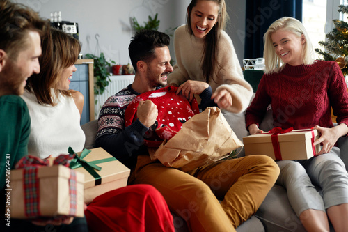 Foto Friends having fun while unwrapping presents