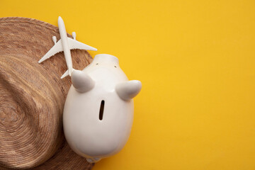 Saving for a summer vacation. Money piggy bank with holiday travel accessories