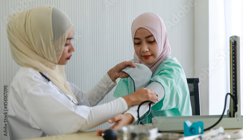 Young female muslim doctor measure blood pressure of a female patient at hospital