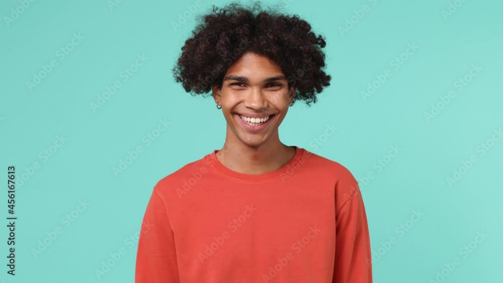 Smiling thoughtful vivid young curly african american man 20s wears azure t-shirt look around think dream lost in thought and conjectures isolated on plain pastel light blue background studio portrait Smiling thoughtful vivid young curly african american man 20s wears azure t-shirt look around think dream lost in thought and conjectures isolated on plain pastel light blue background studio portrait