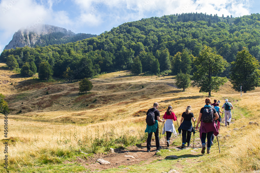 group of hikers in the mountains. landscape with blue sky and one mountain. Romania, Maramures, the mountain Creasta Cocosului