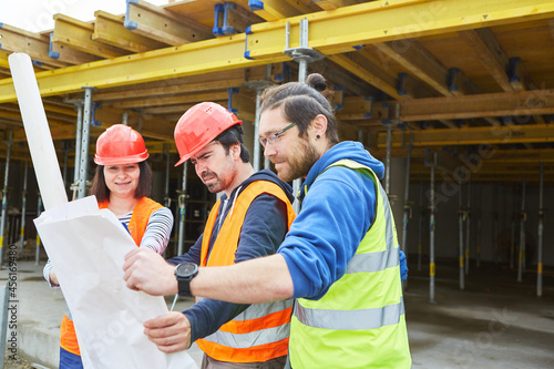 Craftsmen team and architect with building drawing © Robert Kneschke