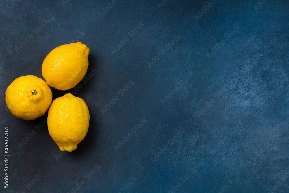 Three bright yellow citrus fruits on a blue background top view