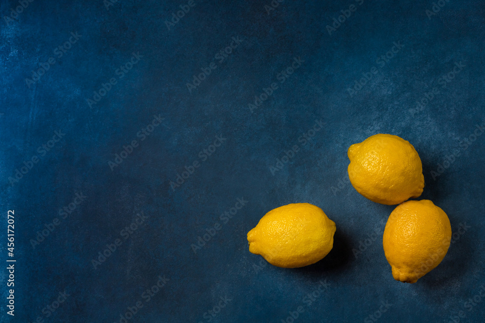 Three bright yellow citrus fruits on a blue background top view Three bright yellow citrus fruits on a blue background top view