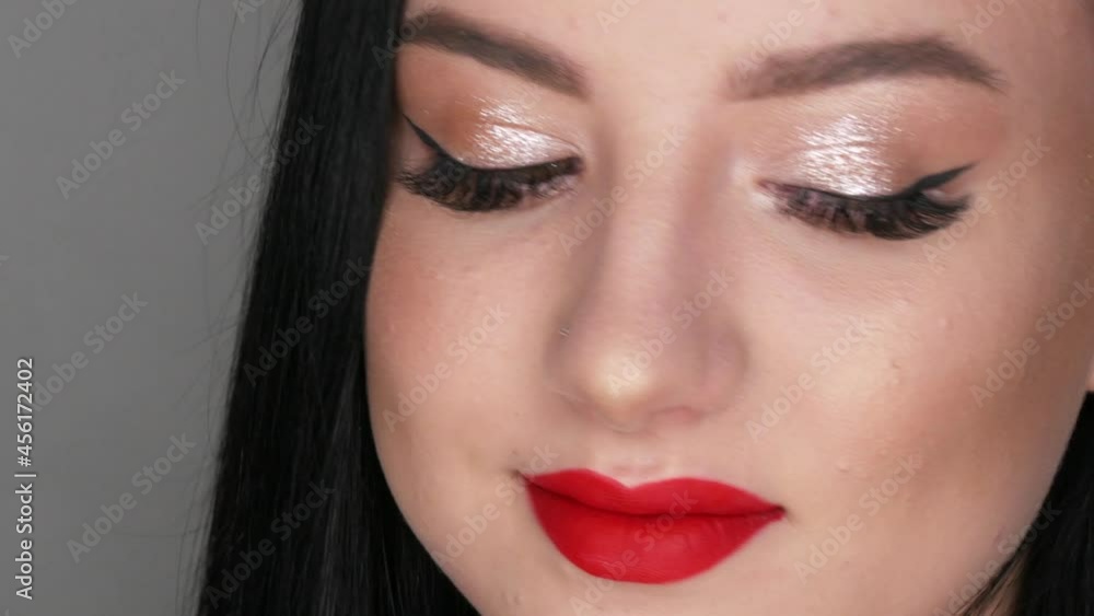 Close up view of beautiful girl model with big lips painted with red lipstick. Young woman posing with bright evening make-up Close up view of beautiful girl model with big lips painted with red lipstick. Young woman posing with bright evening make-up