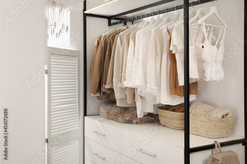 Rack with stylish women's clothes in dressing room