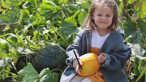 A child paints a scary face on a pumpkin for Halloween. Children are preparing for the feast of all saints. 
