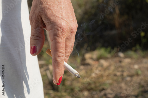 Elderly woman hold burning cigarette while smoking,tobacco smoke,unhealthy lifestyle