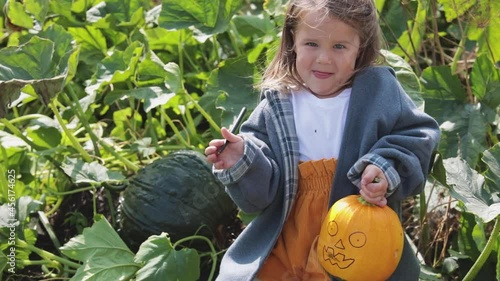 A child paints a scary face on a pumpkin for Halloween. Children are preparing for the feast of all saints. 