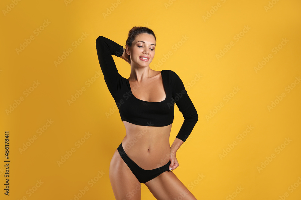 Obraz premium Beautiful woman in black sexy panties on yellow background
