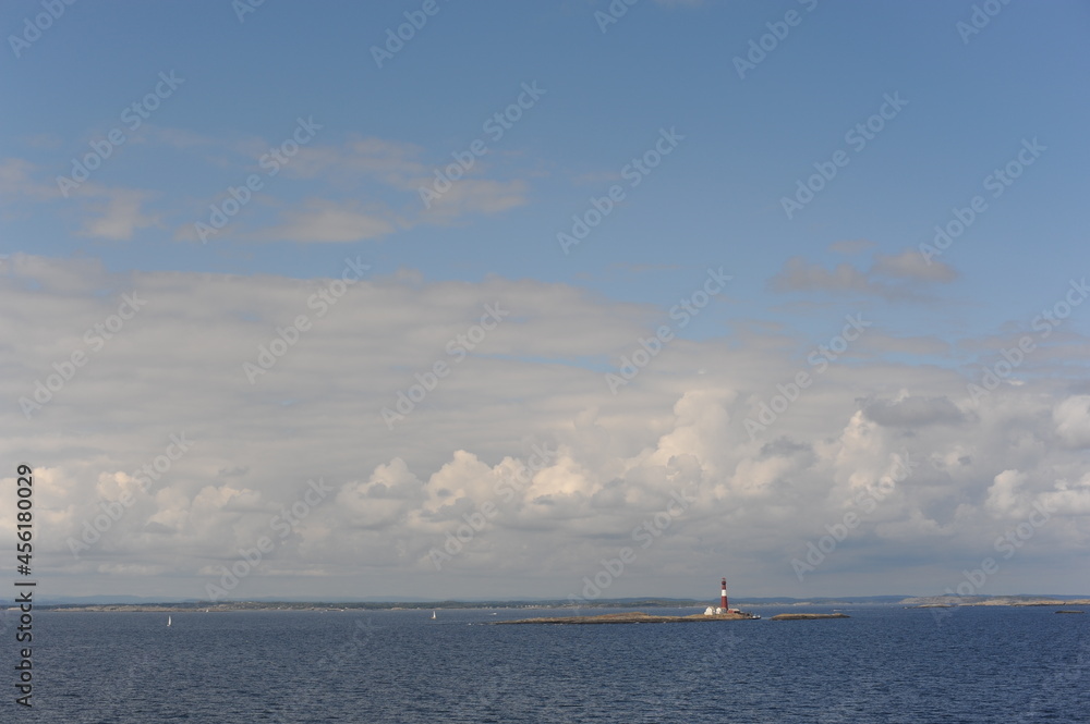 Lighthouse on a tiny uninhabited island in Skagerrak Strait between  Sweden and Norway on a sunny day with blue sky, navy blue sea and white clouds