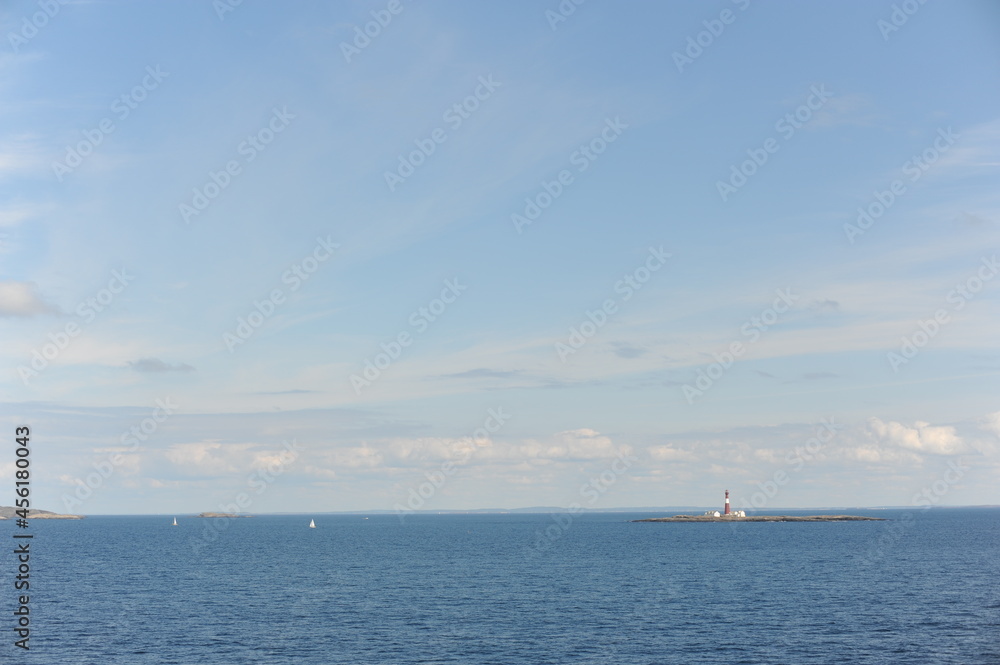 Lighthouse on a tiny uninhabited island in Skagerrak Strait between  Sweden and Norway on a sunny day with blue sky, navy blue sea and white clouds