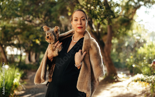 Canvas Print Luxurious woman looking at the camera while holding her puppy