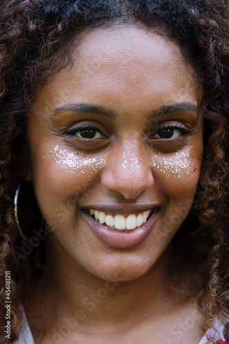 Portrait of a black woman with afro hair and glitter on her face © sashapritchard