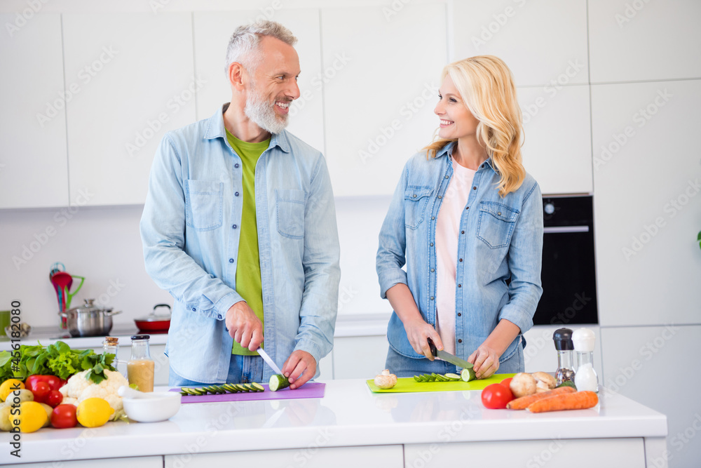 Photo of good mood smiling positive couple prepare meal breakfast together wife and husband cut chop cucumber Photo of good mood smiling positive couple prepare meal breakfast together wife and husband cut chop cucumber