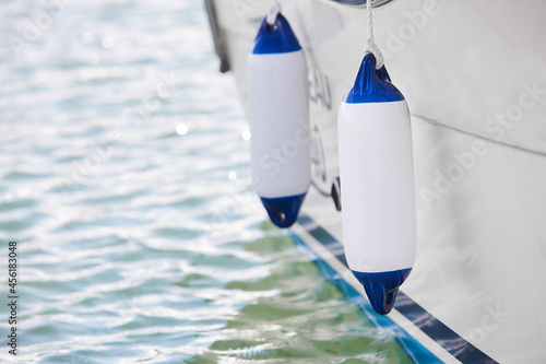 Quadro su tela Two white fenders suspended between a boat and dockside for protection