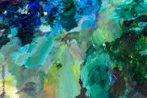 Blue turquoise oil paint close-up. Blurry multicolored background. The artist's professional paints are in selective focus. The concept of creativity, creative ideas, favorite hobby. Painting classes