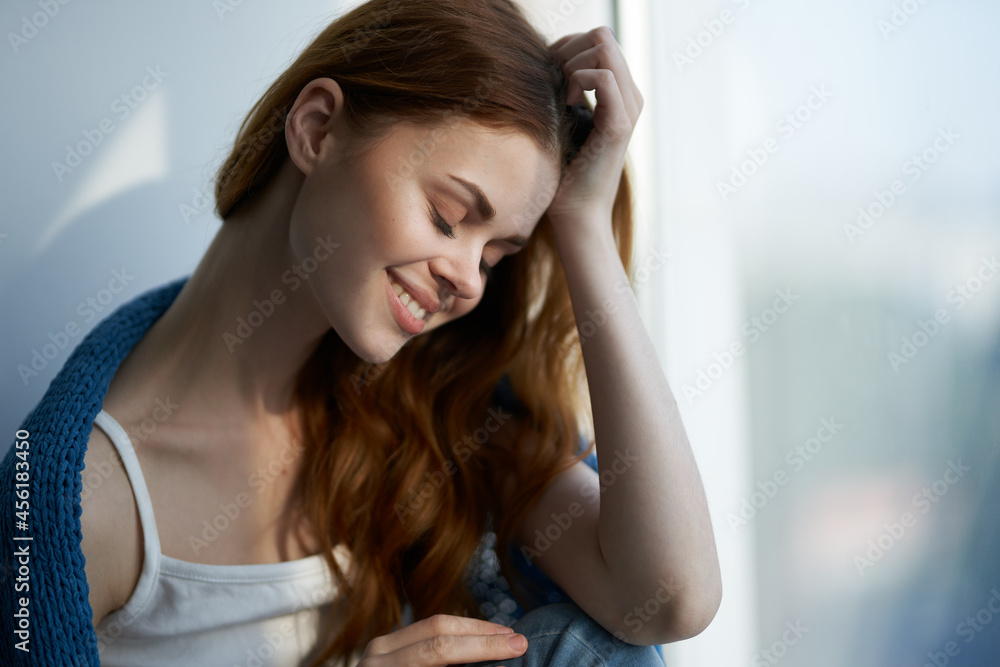 pretty woman sitting near the window with a blue plaid Lifestyle pretty woman sitting near the window with a blue plaid Lifestyle