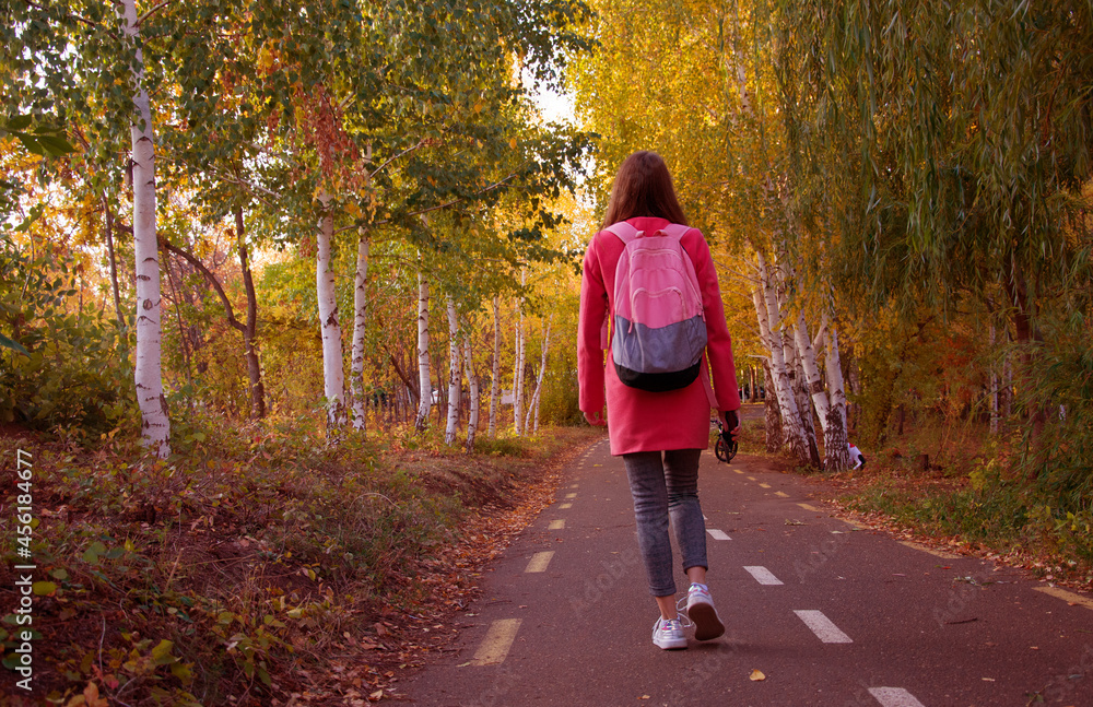 Fototapeta premium Faceless female traveler walking in park in autumn