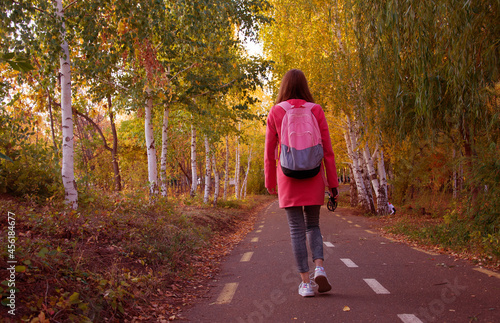 Faceless female traveler walking in park in autumn