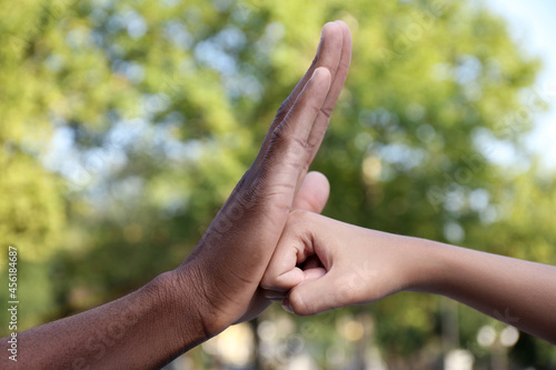 African American man stopping woman's fist outdoors, closeup. Antiracism concept © New Africa