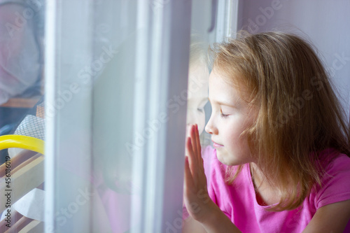 sad girl in a pink dress sits by the window, loneliness concept, isolation