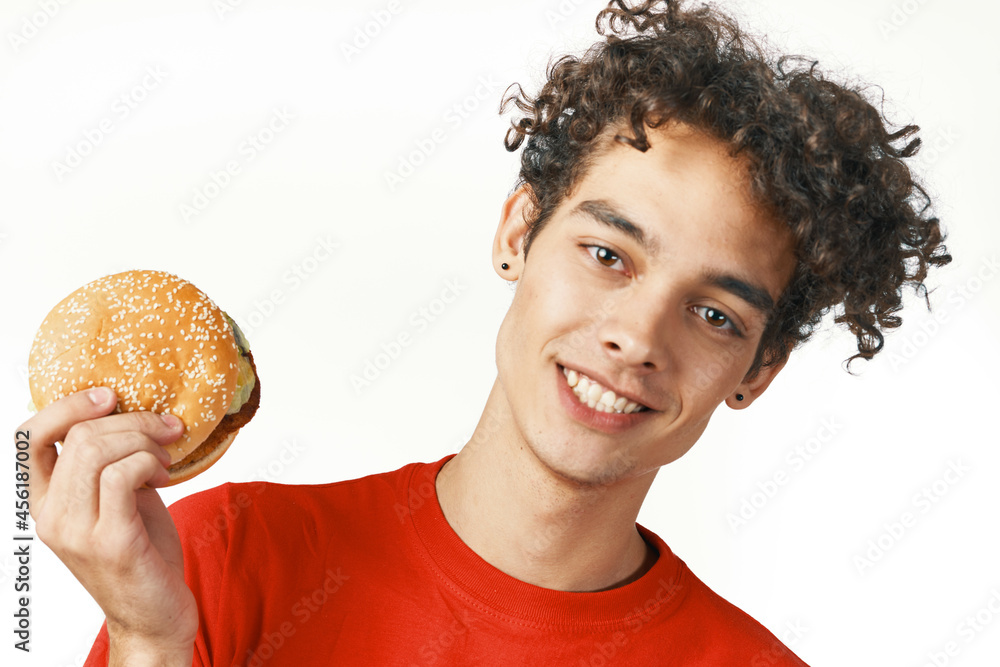 Cheerful curly hamburger guy holding a red t-shirt lifestyle Cheerful curly hamburger guy holding a red t-shirt lifestyle