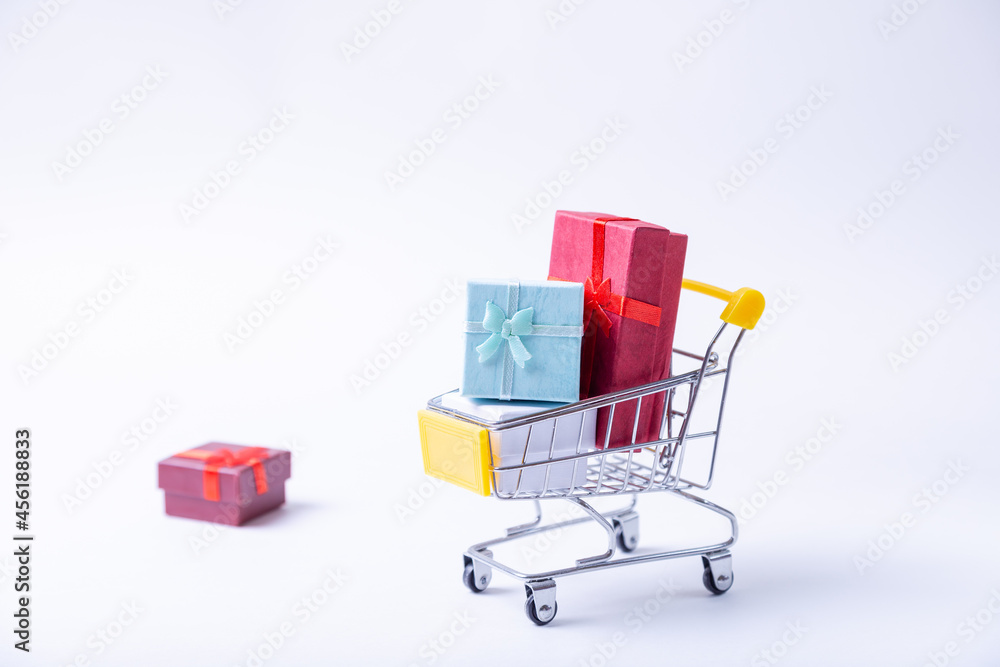 Miniature cart with gifts on a white background. Holidays shopping concept. Close-up. Miniature cart with gifts on a white background. Holidays shopping concept. Close-up.
