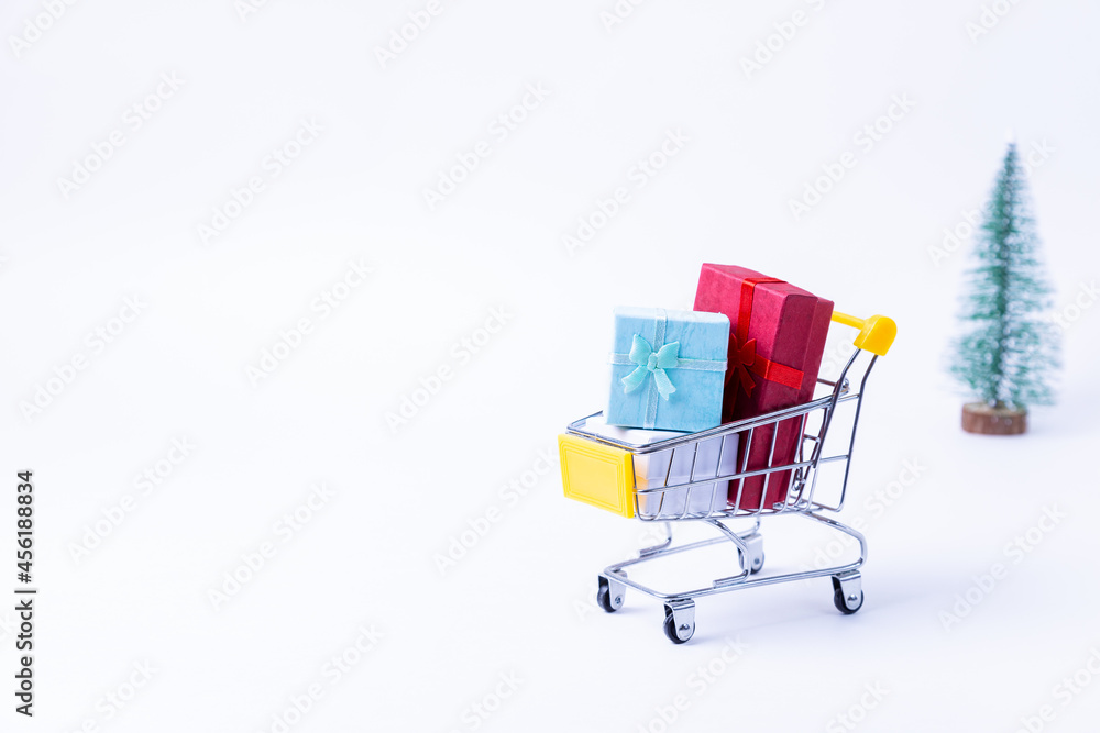 Miniature cart with gifts on a white background. Christmas and New Year shopping concept. Close-up.