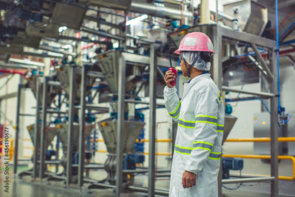 Male engineers sound protection and uniform staff.Hand holding portable radio transceiver for communication work inspection process powder stainless steel tanks Male engineers sound protection and uniform staff.Hand holding portable radio transceiver for communication work inspection process powder stainless steel tanks