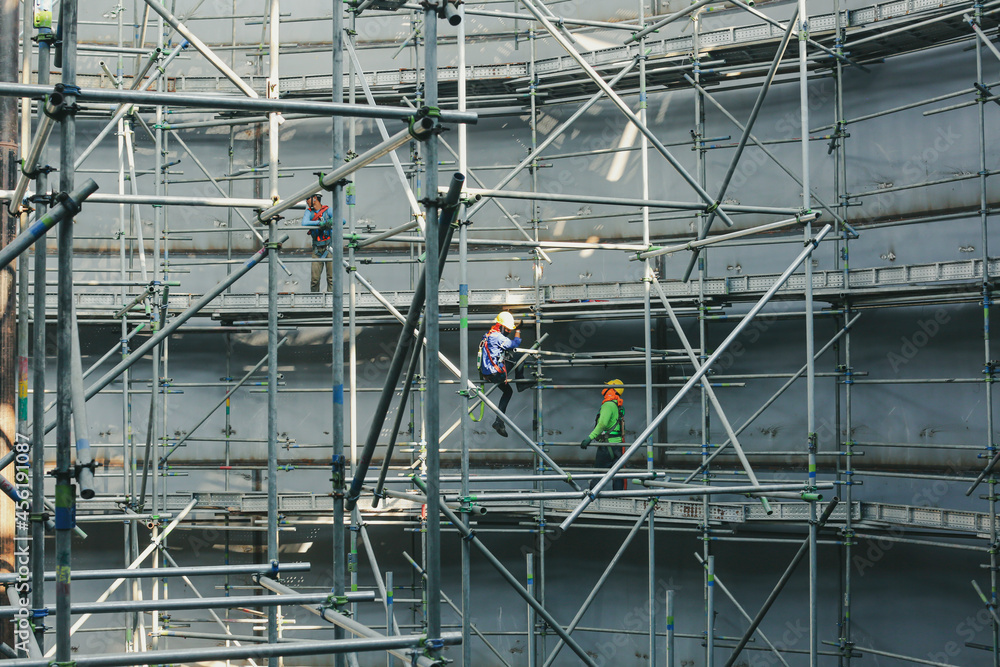 Construction workers tank oil installing scaffolding