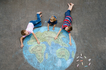 Little preschool girl and two school kids boys with earth globe painting with colorful chalks on ground. Happy earth day concept. Creation of children for saving world, environment and ecology.