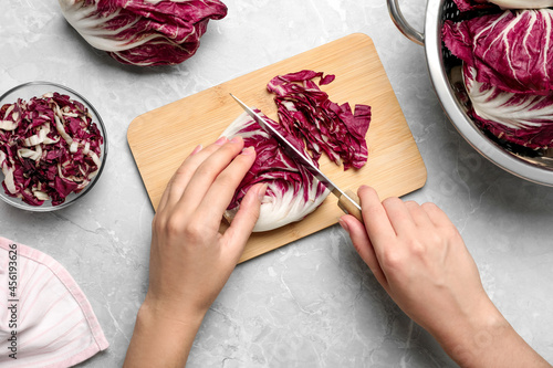 Bilde på lerret Woman cutting fresh ripe radicchio at light grey marble table, top view