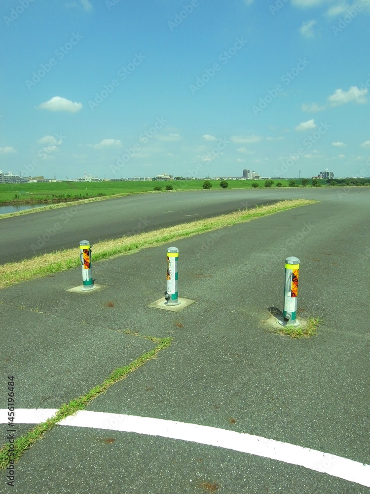 Obraz premium 車止めのある夏の江戸川サイクリング道路風景