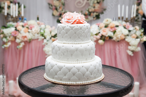 a multi level white wedding cake and pink flowers on top. Big cake.