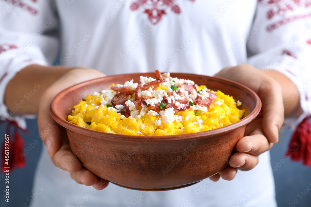 Woman holding bowl of banosh with brynza and pork cracklings, closeup. Traditional Ukrainian dish Woman holding bowl of banosh with brynza and pork cracklings, closeup. Traditional Ukrainian dish