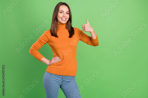 Portrait of attractive cheerful girl showing thumbup ad advert recommend decision isolated over green color background
