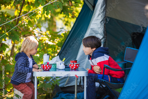 Happy children, eating breakfast in the morning in front of a tent in a campsite in the forest in Sweden beach photo