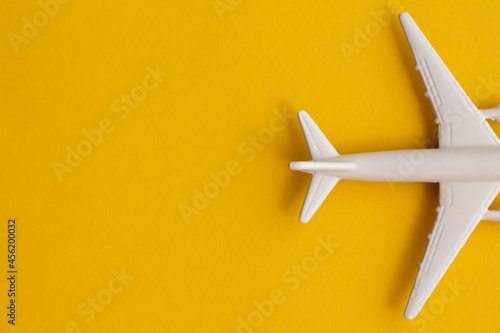 White passenger airplane on a summer yellow background. Travel and vacation background