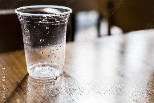 Closed-up a plastic glass of empty water on wooden table for background