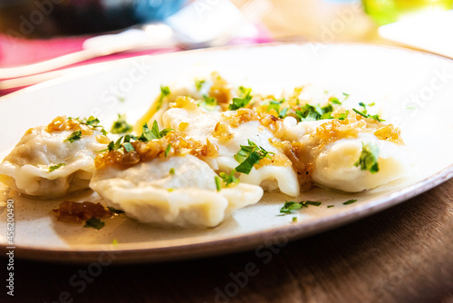 Delicious homemade polish dumplings stuffed with meats and caramelized onions on top served in white plate.